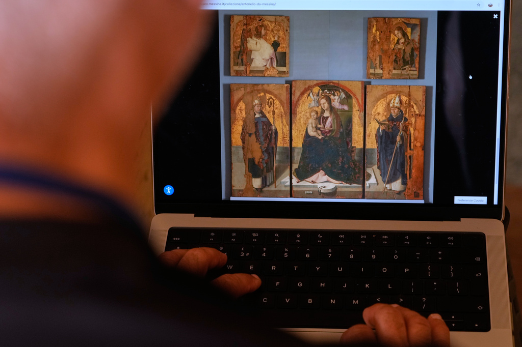 A journalist browses the Messina museum website showing a picture of the Early Renaissance painter Antonello da Messina's artwork where three of the five panels belonging to the Polyptych of San Gregorio and the double-sided panel with the Madonna and the Christ in Pietà, stolen from the Sicilian museum on Aug. 15, in Rome, Sunday, Aug. 16, 2026. (AP Photo/Gregorio Borgia)