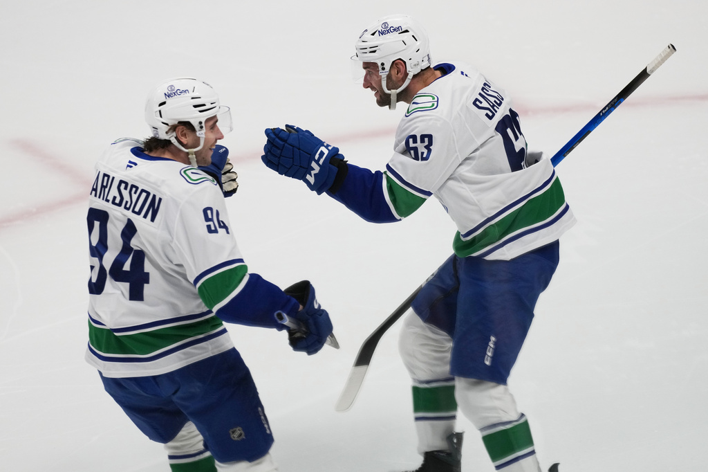 Vancouver Canucks center Linus Karlsson, left, congratulates center Max Sasson after his goal against the Colorado Avalanche in the first period of an NHL hockey game Wednesday, April 1, 2026, in Denver. (AP Photo/David Zalubowski)