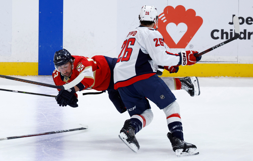 Washington Capitals center Nic Dowd (26) watches Florida Panthers left wing Brad Marchand (63) who wastripped by right wing Ryan Leonard during the second period of an NHL hockey game, Monday, Dec. 29, 2025, in Sunrise, Fla. (AP Photo/Rhona Wise)