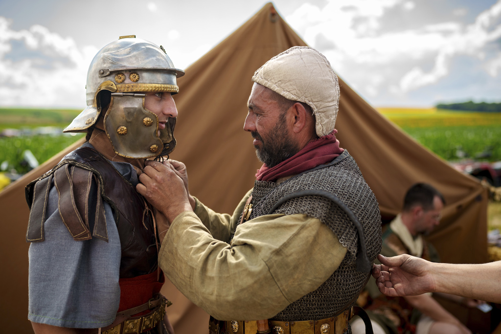 Ondrej Kohut, left, of the Legio X Gemina Coh II, Roman era military historical group with members from the Czech Republic and Slovakia, has his Roman soldier outfit adjusted by colleague Ludovic Kohut in Poiana, Romania, Saturday, July 12, 2025, during the Getodava historical reenactment festival. (AP Photo/Vadim Ghirda)