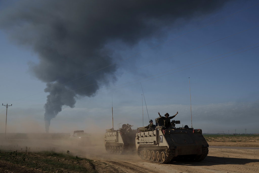 Israeli soldiers ride in armored personnel carriers (APC) near the Israeli-Gaza border as smoke rises in the Gaza Strip, seen from southern Israel, Sunday, Jan. 21, 2024. (AP Photo/Leo Correa)