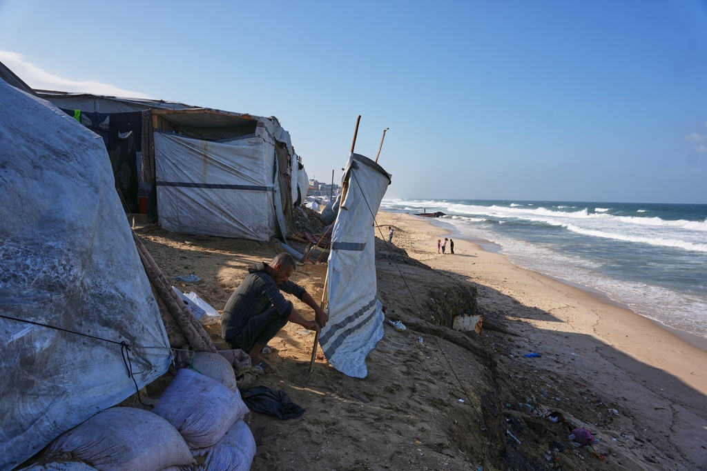 Saed Mahmoud, 42, reinforces his tent after it was damaged by a storm at a temporary camp on the beach in Deir al-Balah, in the central Gaza Strip, Saturday, Nov. 15, 2025. (AP Photo/Abdel Kareem Hana)