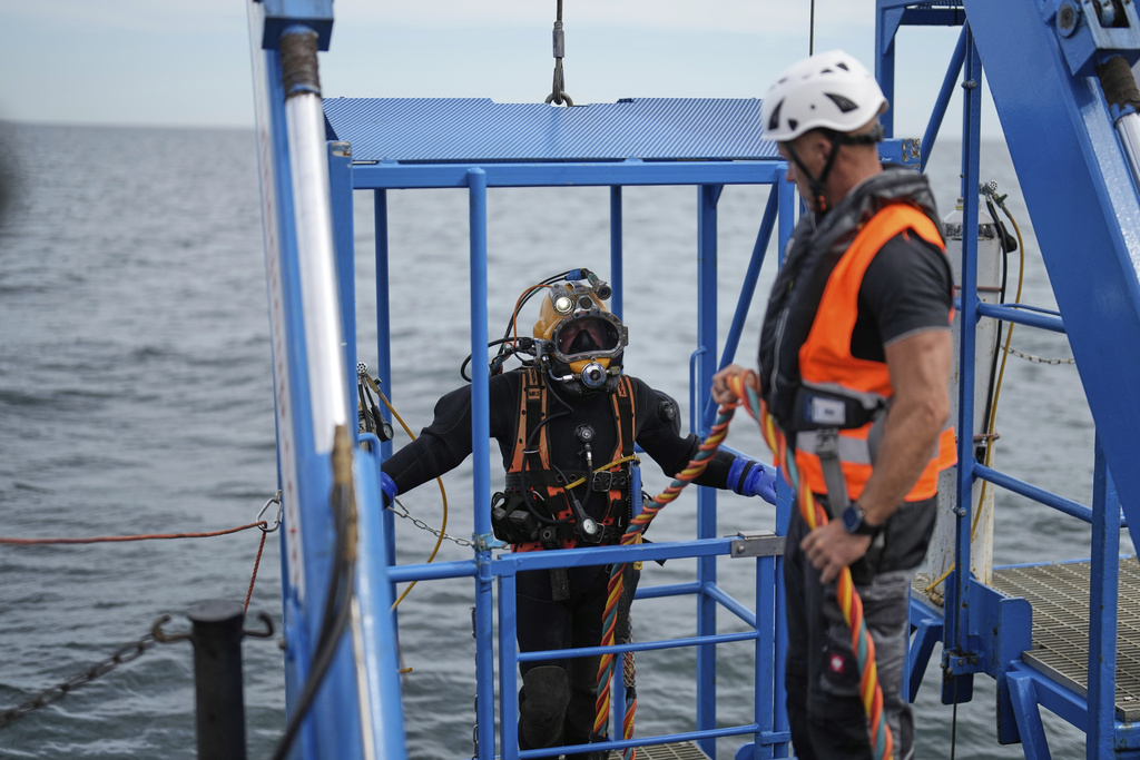 A diver is lowered into the water during a press tour to show the recovering of ammunition from World War II in the Baltic Sea near Boltenhagen, Germany, Monday, Sept. 1, 2025. (AP Photo/Markus Schreiber)