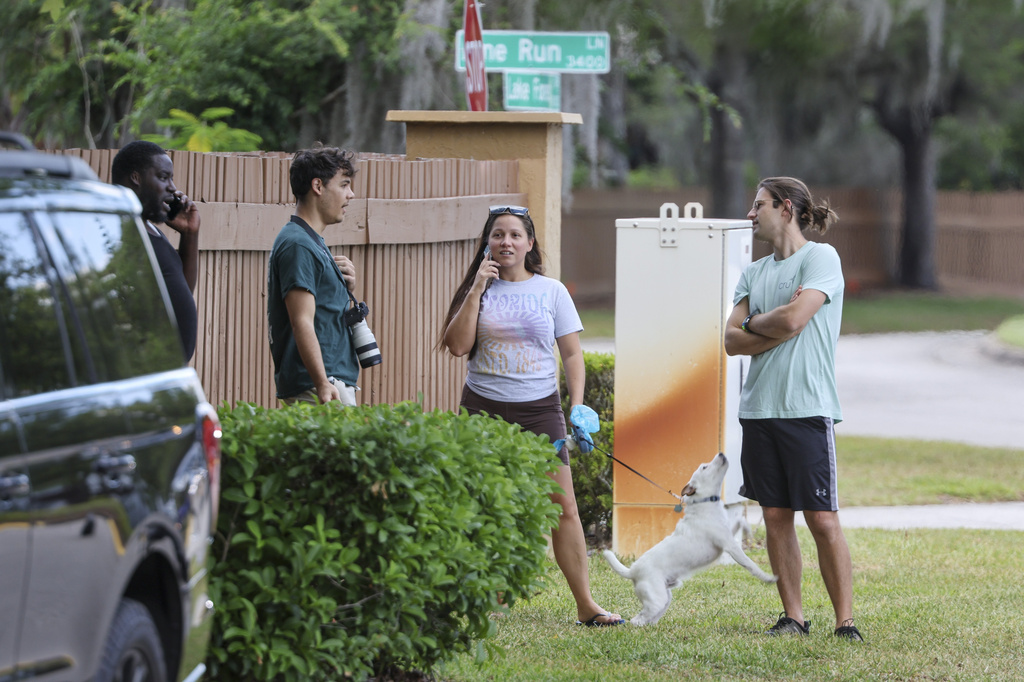 People gather near the entrance of the Lake Forest subdivision of Tampa, Fla., on Friday, April 24, 2026, where authorities said a man was taken into custody after barricading himself inside a home, in connection to the search for two missing University of South Florida graduate students. (Douglas R. Clifford/Tampa Bay Times via AP)