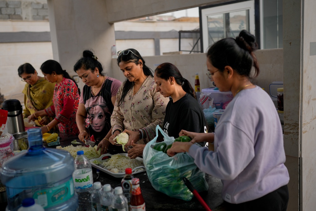 Stranded Indian travelers help prepare food at a farmhouse owned by an Indian businessman, now converted into a shelter in Ajman, near Dubai, United Arab Emirates, Saturday, March 7, 2026. (AP Photo/Altaf Qadri)