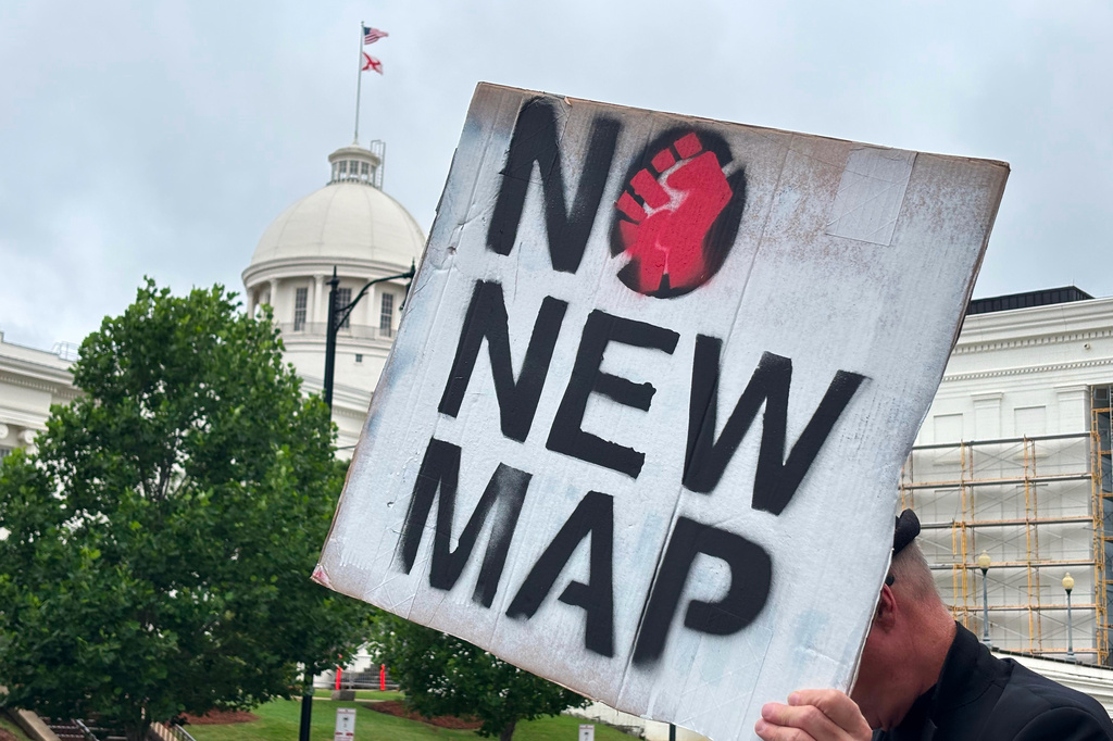 A demonstrator holds up a sign outside the Alabama Statehouse in Montgomery, Ala., on Thursday, May, 7 2026. (AP Photo/Kim Chandler)