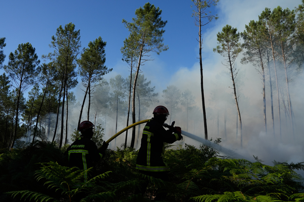 Firefighters work to suppress a fire near Lacanau, as wildfires rage outside Bordeaux, France, Monday, July 27, 2026. (AP Photo/Baz Ratner)