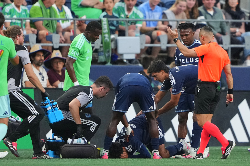 Vancouver Whitecaps midfielder Jeevan Badwal is checked for a concussion as Seattle Sounders defender Nouhou Tolo, third from left, looks on during the first half of an MLS soccer match against the Seattle Sounders, Sunday, Aug. 16, 2026, in Seattle. (AP Photo/Lindsey Wasson)