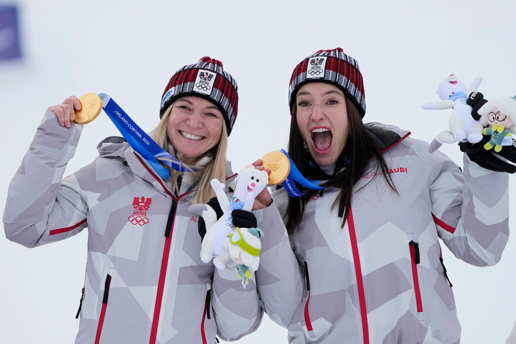 Austria's Ariane Raedler, left, and teammate Austria's Katharina Huber show their gold medals in an alpine ski, women's team combined race, at the 2026 Winter Olympics, in Cortina d'Ampezzo, Italy, Tuesday, Feb. 10, 2026. (AP Photo/Andy Wong)