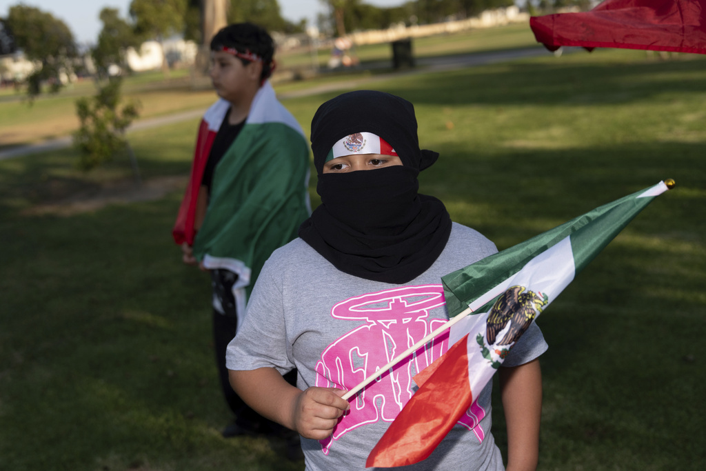 Brandon Gomez, 10, who said his classmate's parents were detained by ICE, joins other demonstrators protesting a recent raid, covering his face out of fear of being identified, in Oxnard, Calif., Friday, July 18, 2025. (AP Photo/Jae C. Hong)