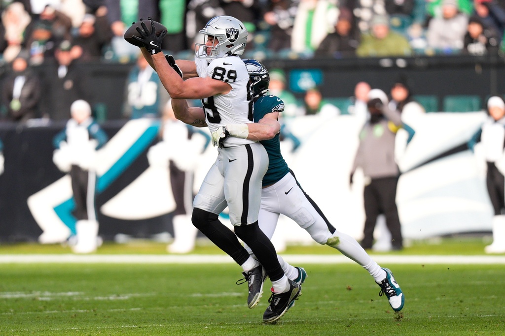 Las Vegas Raiders tight end Brock Bowers (89) catches the ball as he's brought down by Philadelphia Eagles cornerback Cooper Dejean (33) during the first half of an NFL football game Sunday, Dec. 14, 2025, in Philadelphia. (AP Photo/Chris Szagola)