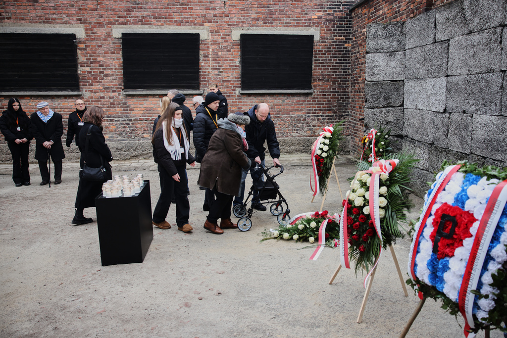 Holocaust survivors lay flowers at the death wall in the Auschwitz Nazi death camp museum during a ceremony marking the 81th anniversary of the camp's liberation in Oswiecim, Poland, Tuesday, Jan. 27, 2026. (AP Photo/Beata Zawrzel)