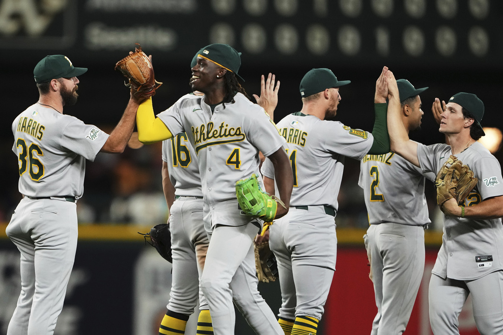Athletics center fielder Lawrence Butler (4) greets pitcher Hogan Harris (36) as they celebrate a win over the Seattle Mariners in 10 innings of a baseball game Saturday, Aug. 23, 2025, in Seattle. (AP Photo/Lindsey Wasson)