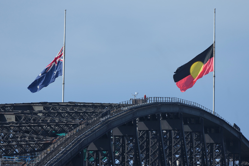 Australian and Aboriginal flags fly at half staff on the Sydney Harbour Bridge during a National Day of Reflection to honour the victims of the last Sunday's terrorist attack at Bondi Beach, Sunday, Dec. 21, 2025. (AP Photo/Mark Baker)