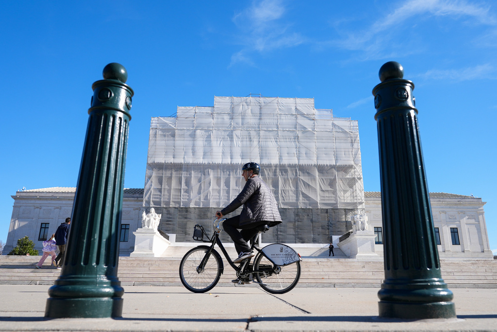 As a person on a bicycle rides past, construction on the front of the U.S. Supreme Court continues Monday, Nov. 24, 2025, in Washington. (AP Photo/Mariam Zuhaib)