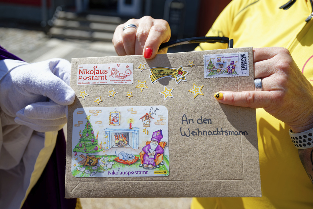 Santa Claus hands a postal envelope to Post employee Simone Nehring in St. Nikolaus, Germany, Saturday Aug. 9, 2025. (Uwe Anspach/dpa via AP)