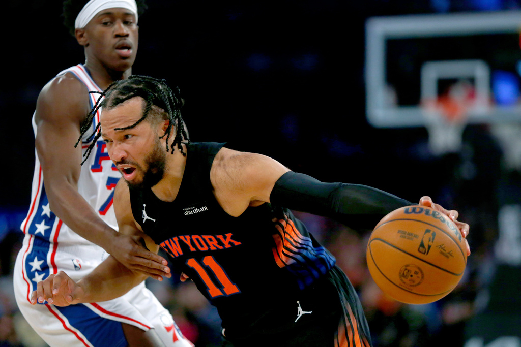 New York Knicks guard Jalen Brunson, right, dribbles around Philadelphia 76ers guard VJ Edgecombe during the first half of an NBA basketball game, Friday, Dec. 19, 2025, in New York. (AP Photo/John Munson)