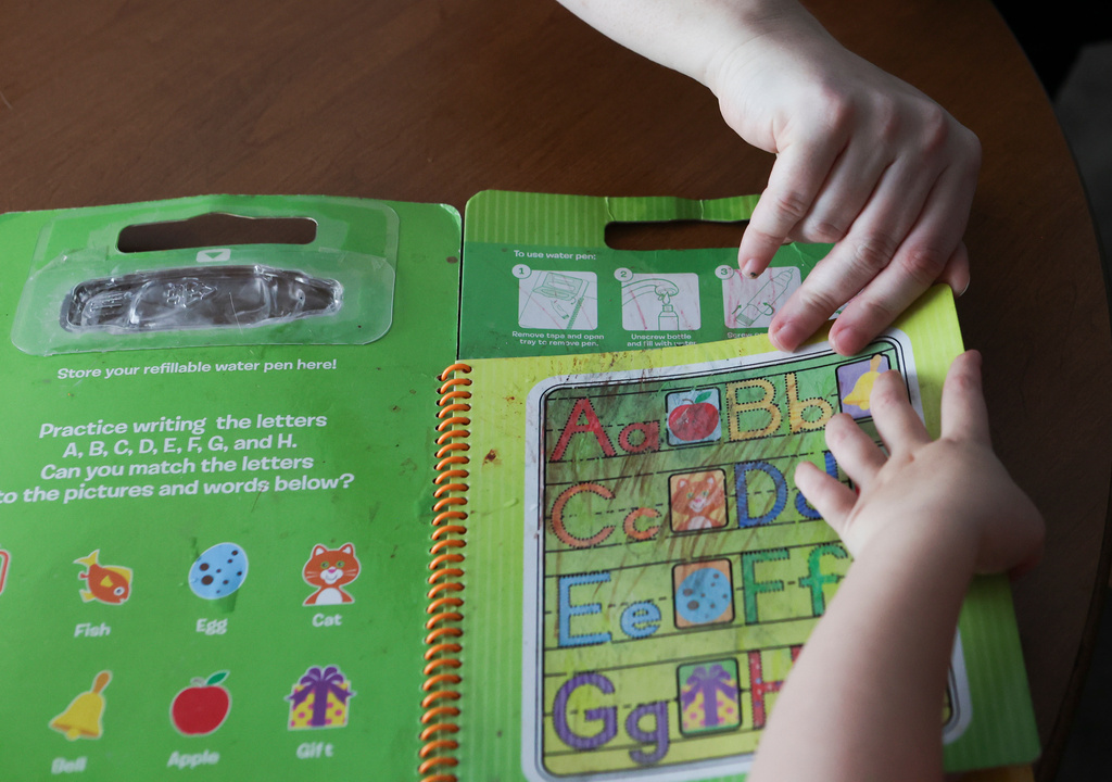 Meygan Maloney looks through a toy with her son Callum Wilson, 3, Friday, Aug. 28, 2026, at their home in Hartford City, Ind. (AP Photo/Cara Penquite)