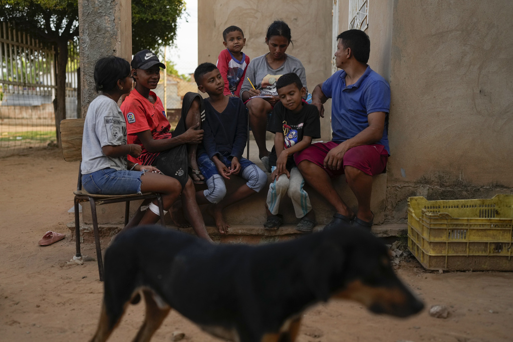 Jose Romero, right, his wife Yoselin Perez and their five children, who returned to Venezuela from Mexico after abandoning plans to reach the United States amid President Donald Trump's migration crackdown, sit on their porch in Maracaibo, Venezuela, Monday, June 16, 2025. (AP Photo/Matias Delacroix)