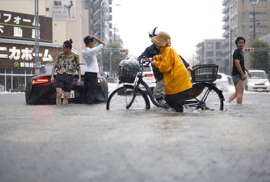 People cross the flooded streets following a heavy rain in Nagoya, central Japan Tuesday, Sept. 8, 2026. (Natsumi Yasumoto/Kyodo News via AP)