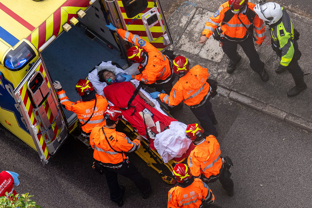 Health workers evacuate a woman from a fire which broke out at Wang Fuk Court, a residential estate in the Tai Po district of Hong Kong's New Territories, Thursday, Nov. 27, 2025. (AP Photo/Chan Long Hei)
