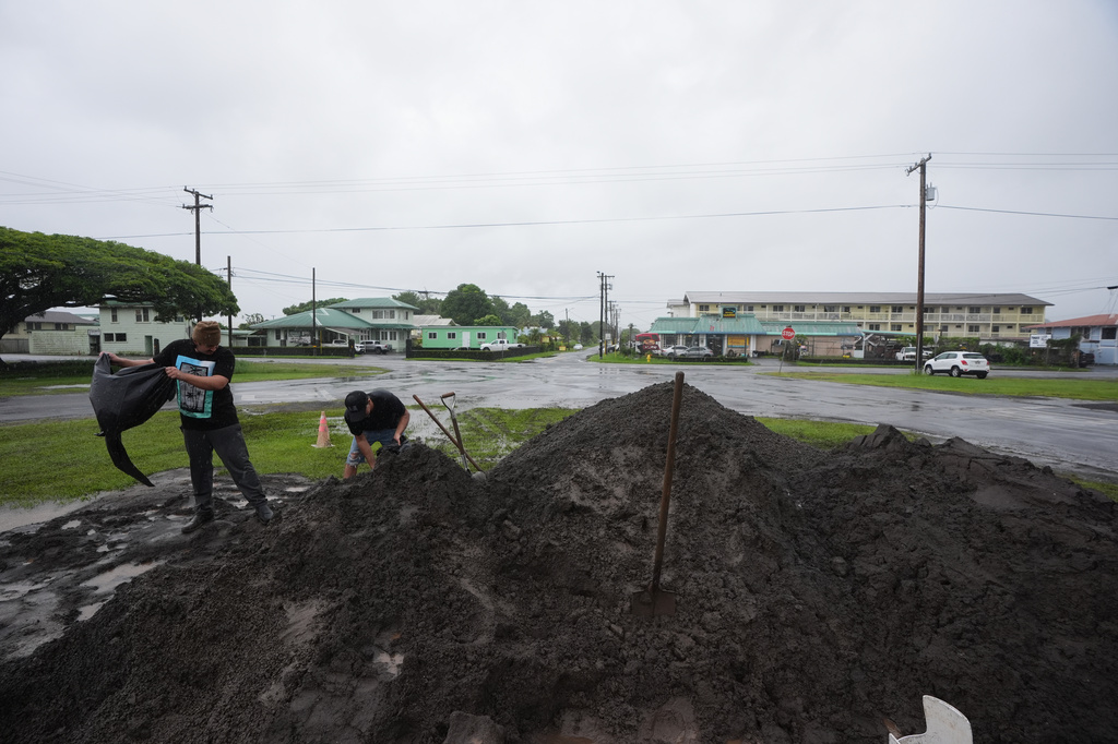 Austin, left, and Darren Montalvo load sand bags to help keep water out of their restaurant as Hurricane Nolo sits nearby Friday, Sept. 25, 2026, in Hilo, Hawaii. (AP Photo/Gregory Bull)