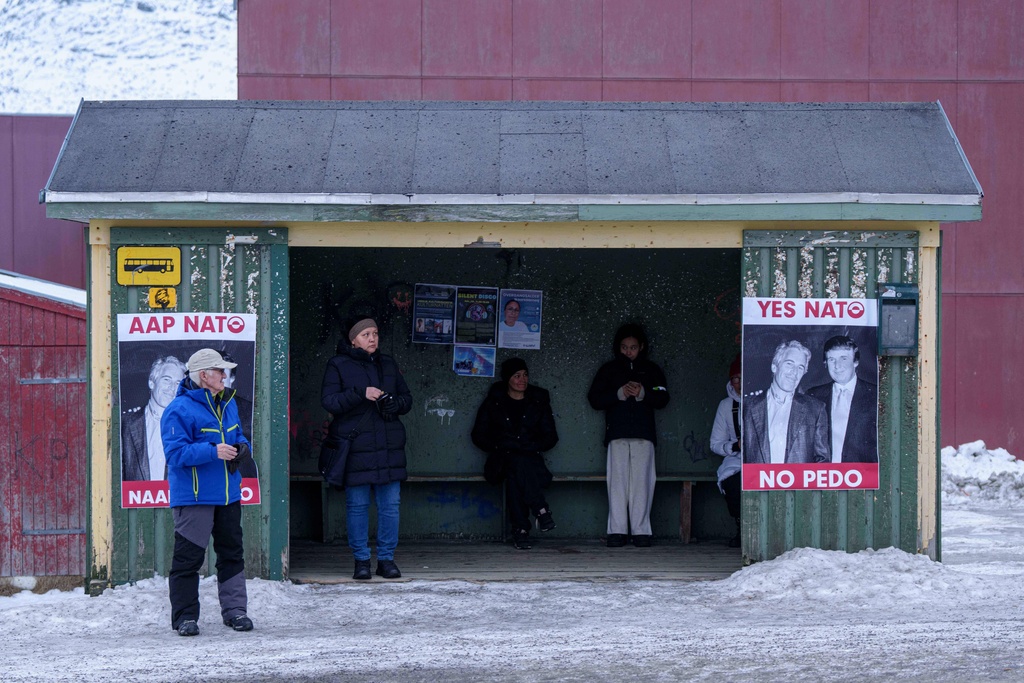 People wait at a bus station with posters of President Donald Trump and Jeffrey Epstein in Nuuk, Greenland, on Saturday, Jan. 24, 2026. (AP Photo/Evgeniy Maloletka)
