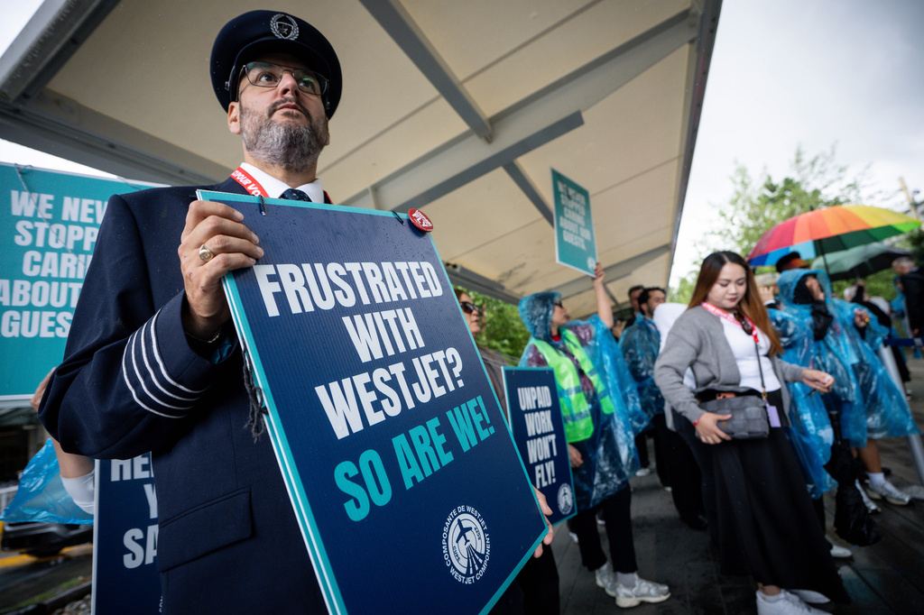 A pilot pickets with WestJet flight attendants on strike at Vancouver International Airport in Richmond, British Columbia, Sunday, Aug. 2, 2026. (Ethan Cairns/The Canadian Press via AP)