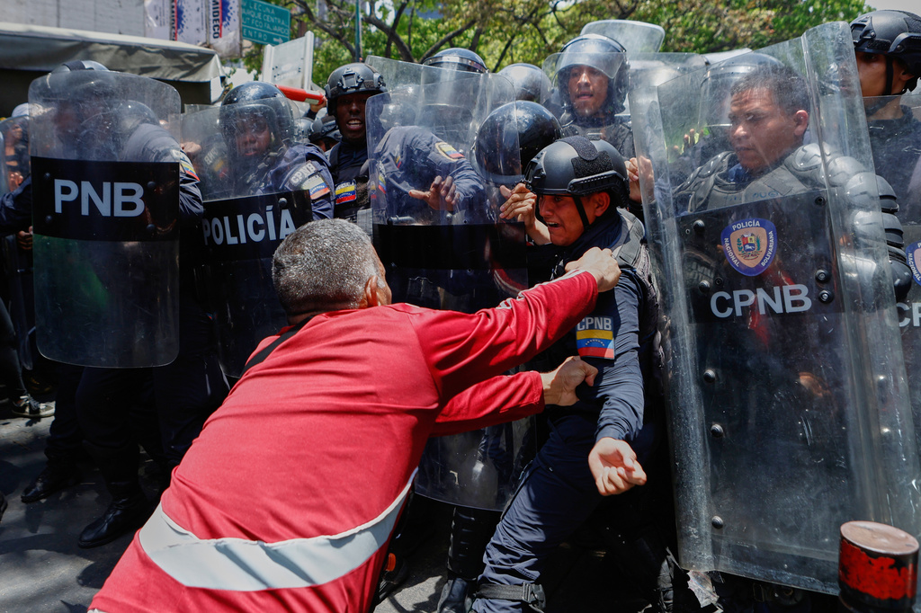 A protester grabs a Bolivarian National Police officer as police try to stop protesters who are demanding higher salaries, pensions and benefits, from continuing their march to the Miraflores Presidential Palace in Caracas, Venezuela, Thursday, April 9, 2026. (AP Photo/Pedro Mattey)