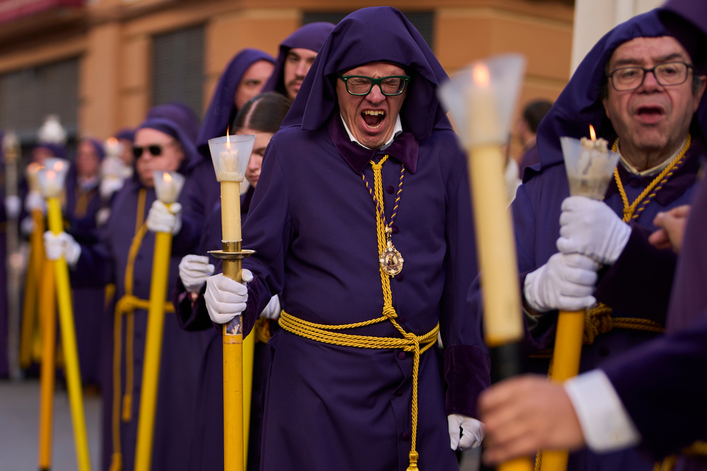 A penitent of the "Hermandad de Nuestro Padre Jesus Nazareno" yawns during a Holy Week procession in Puente Genil, southern Spain, Friday, April 3, 2026. (AP Photo/Manu Fernandez)