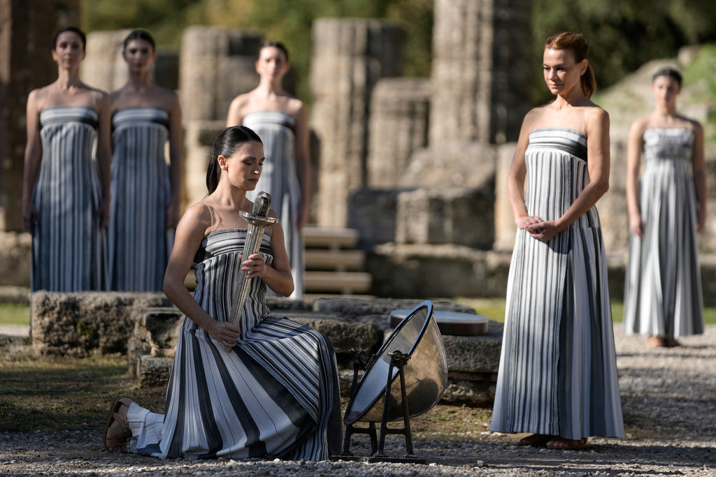 Actor Mary Mina playing the role of high priestess, left, performs during a rehearsal ahead of the flame lighting for the Milan Cortina 2026 Winter Olympics, at the Ancient Olympia site, Greece, Monday, Nov. 24, 2025. (AP Photo/Thanassis Stavrakis)