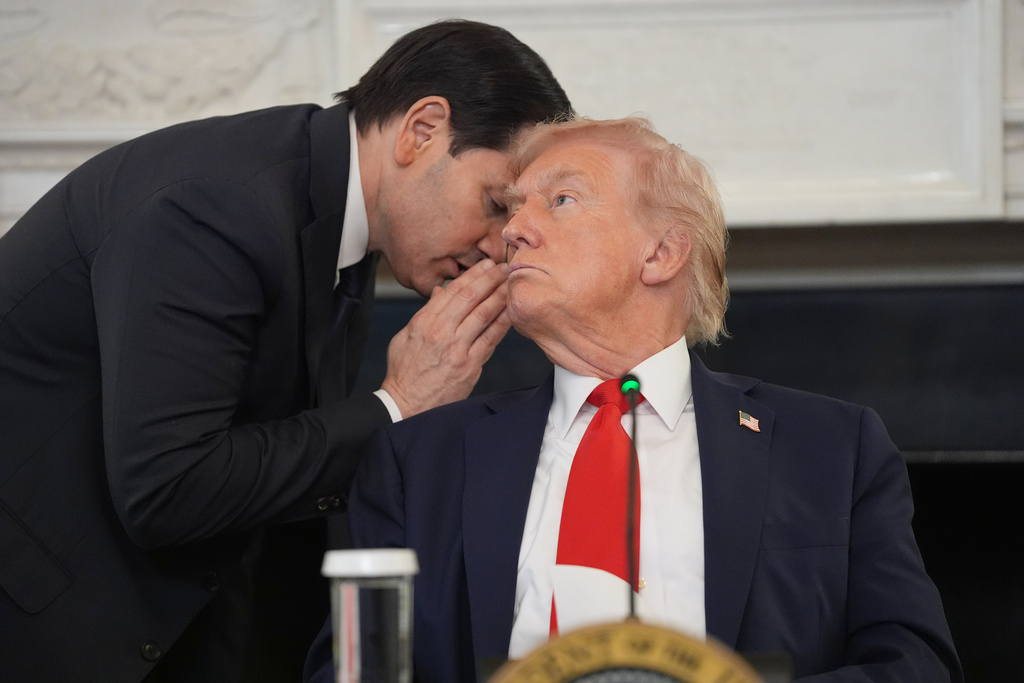 Secretary of State Marco Rubio whispers to President Donald Trump, who is holding the note Rubio handed to him, during a roundtable meeting on antifa in the State Dining Room at the White House, Wednesday, Oct. 8, 2025, in Washington. (AP Photo/Evan Vucci)