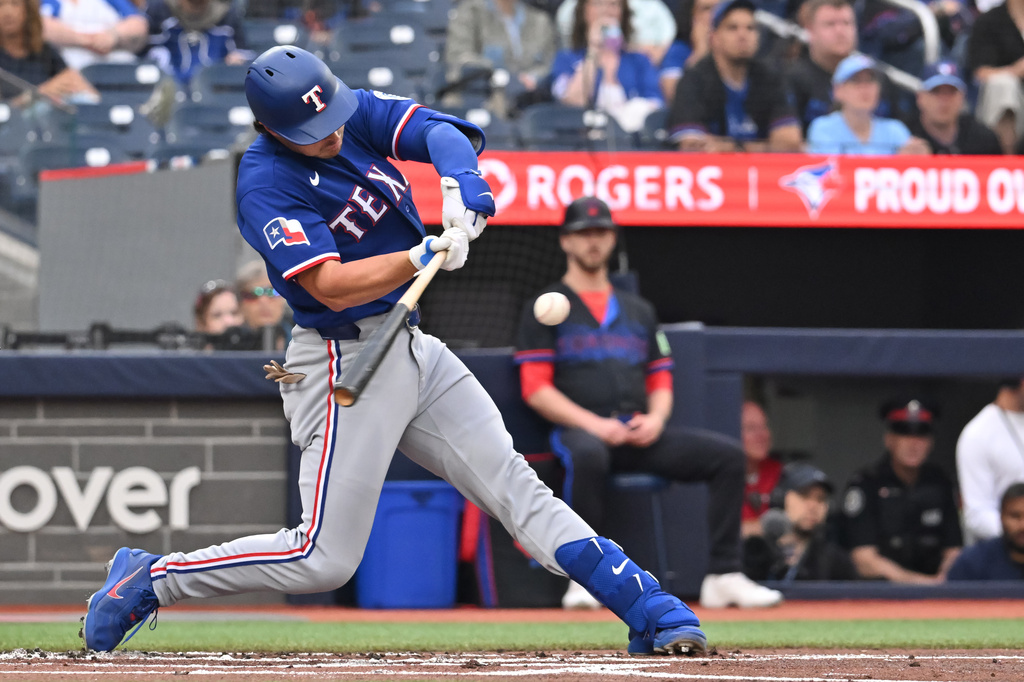 Texas Rangers designated hitter Justin Foscue hits an RBI single against the Toronto Blue Jays during the first inning of a baseball game in Toronto, Friday June 26, 2026. (Jon Blacker/The Canadian Press via AP)
