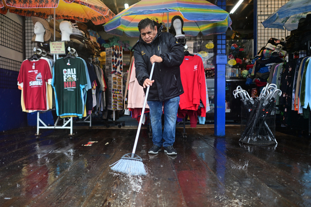 Miguel Lopez sweeps water from Marlene's Beachcomber on the Santa Monica pier Wednesday, Dec. 24, 2025, in Santa Monica, Calif. (AP Photo/Wally Skalij)