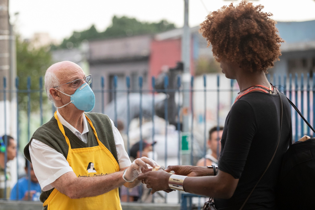 FILE - Priest Julio Lancellotti hands food to a homeless person in Sao Paulo, Brazil, April 3, 2020. (AP Photo/Andre Penner, File)