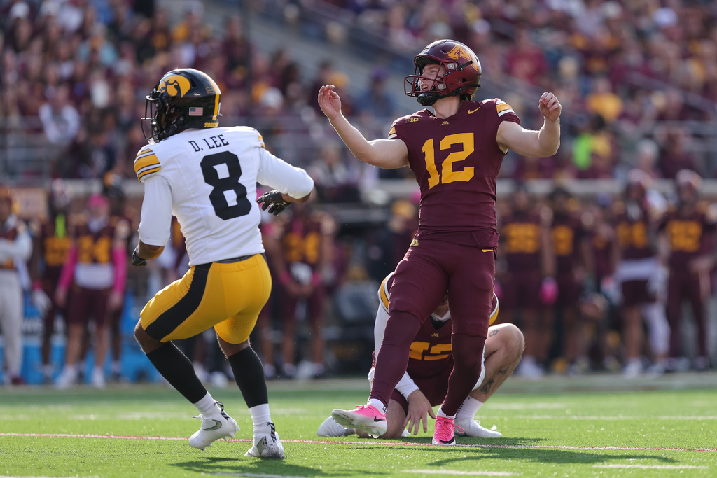 Minnesota kicker Luke Drzewiecki (12) kicks a field goal while Iowa defensive back Deshaun Lee (8) looks on during the first half of an NCAA college football game Saturday, Oct. 24, 2026, in Minneapolis. (AP Photo/Bailey Hillesheim)