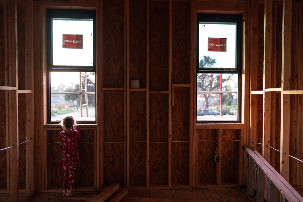 Lupe Figueroa, 5, looks out the window of what will be her room at her family's rebuilding site in Altadena, Calif., Friday, Dec. 19, 2025, months after the Eaton Fire. (AP Photo/Jae C. Hong)