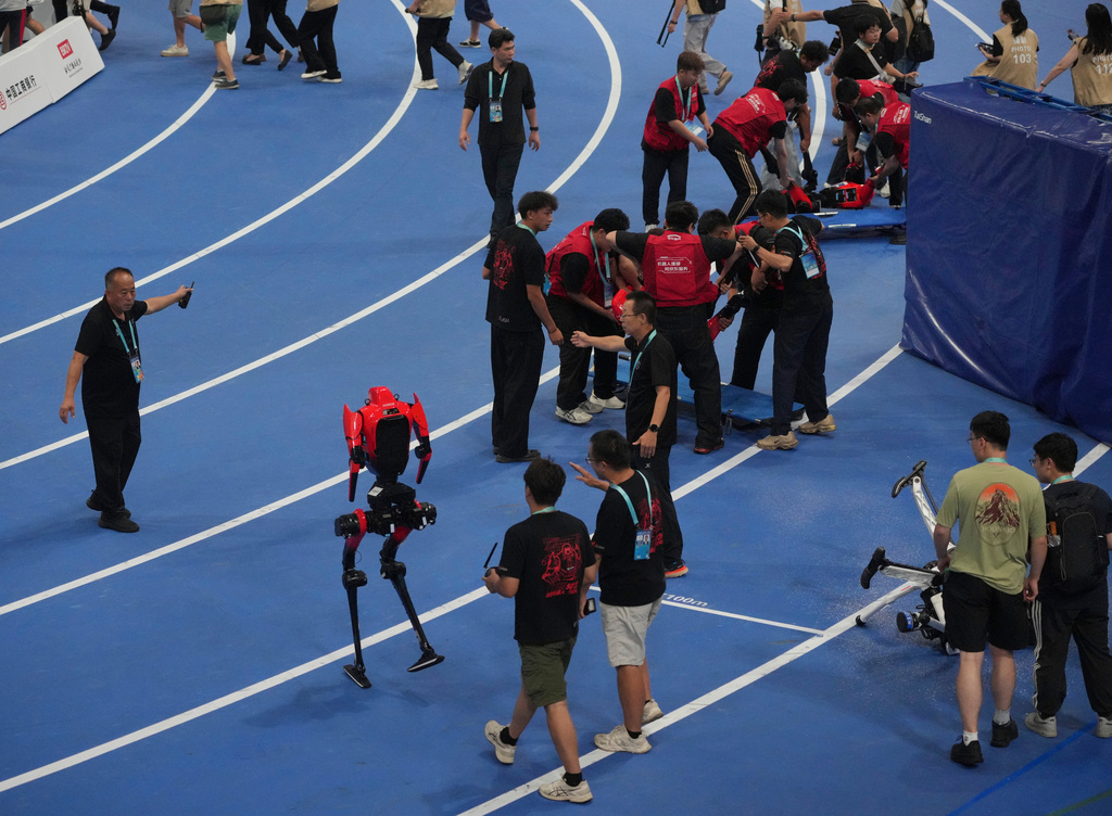 Humanoid robots are carried off the track after competing in the 100m race during the World Humanoid Robot Games in Beijing, Tuesday, Aug. 25, 2026. (AP Photo/Achmad Ibrahim)