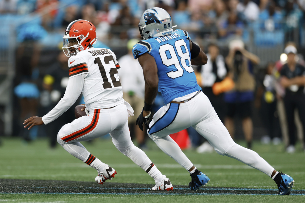 Cleveland Browns quarterback Shedeur Sanders is pursued by Carolina Panthers linebacker D.J. Wonnum during the first half of a preseason NFL football game on Friday, Aug. 8, 2025, in Charlotte, N.C. (AP Photo/Rusty Jones)