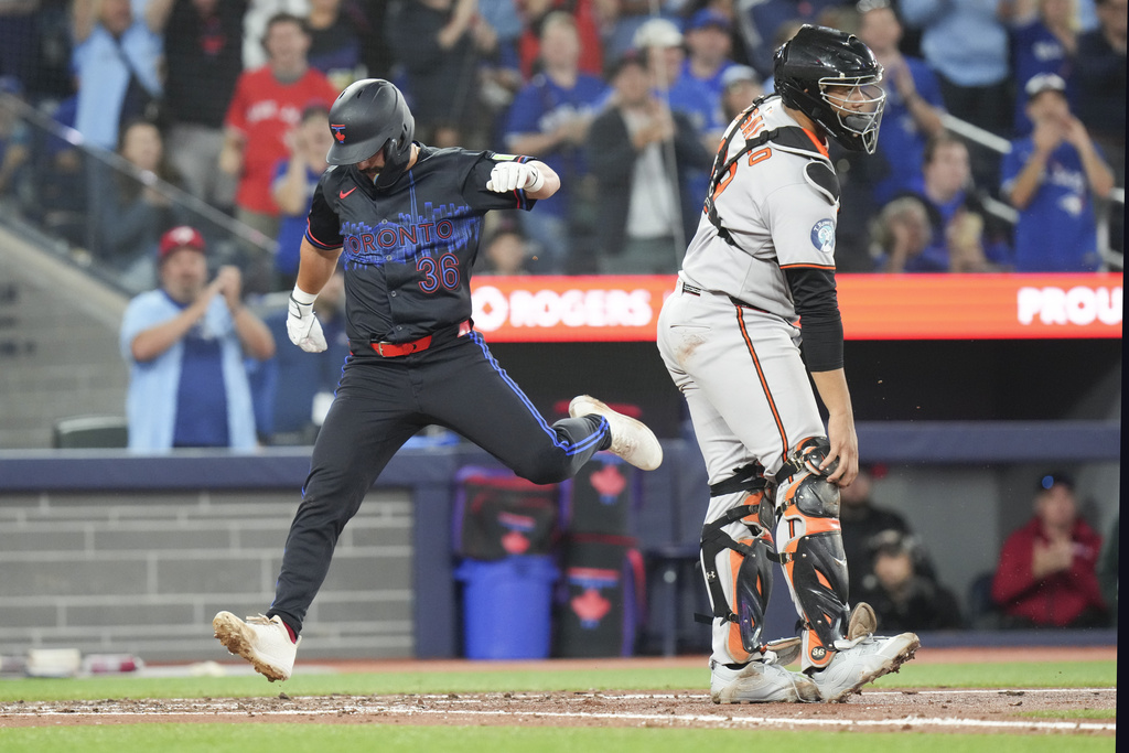 Toronto Blue Jays' Davis Schneider (36) scores as Baltimore Orioles catcher Samuel Basallo (29) looks on during fifth inning MLB baseball action in Toronto, Friday Sept. 12, 2025. (Chris Young/The Canadian Press via AP)