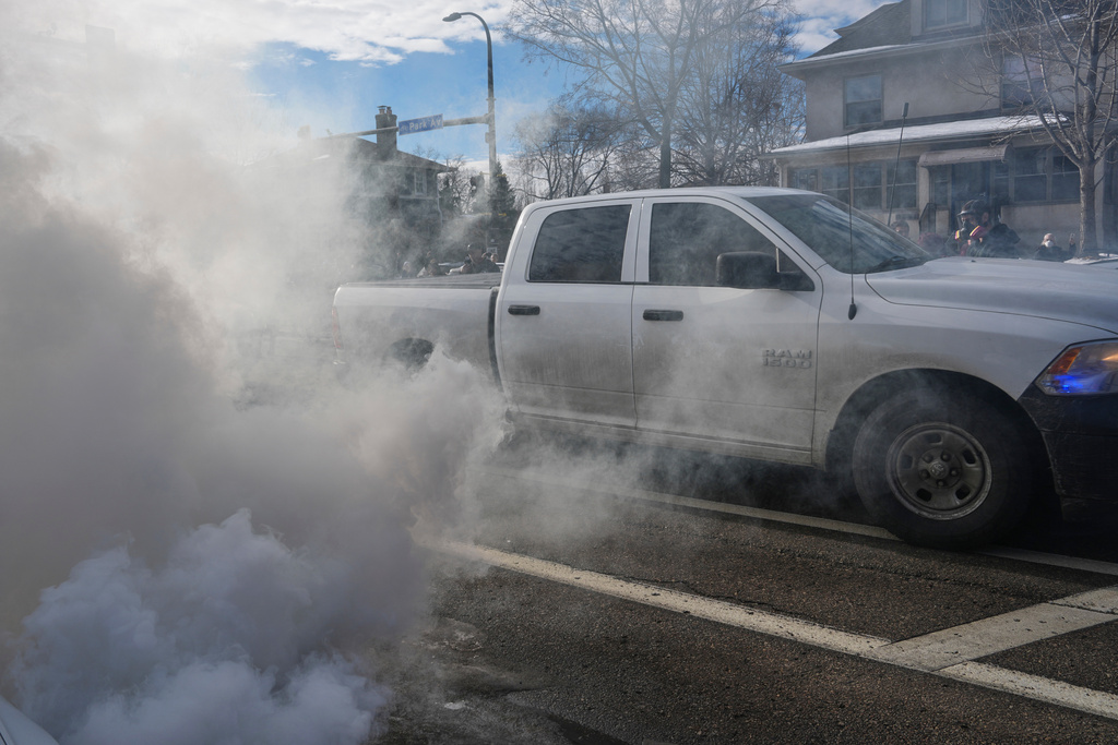 Federal agents drive through smoke from tear gas dispersed during a protest, Monday, Jan. 12, 2026 in Minneapolis (AP Photo/Adam Gray)
