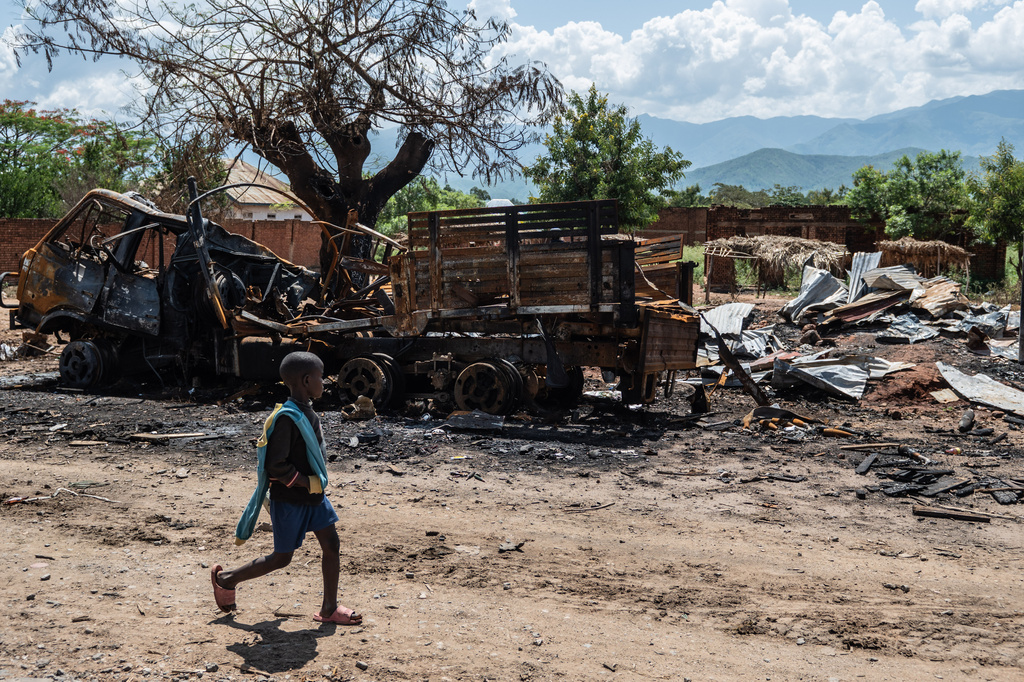 A boy walks past a burned-out vehicle as residents return to their homes in Luvungi, Democratic Republic of Congo, Saturday, Dec. 13, 2025. (AP Photo/Moses Sawasawa)