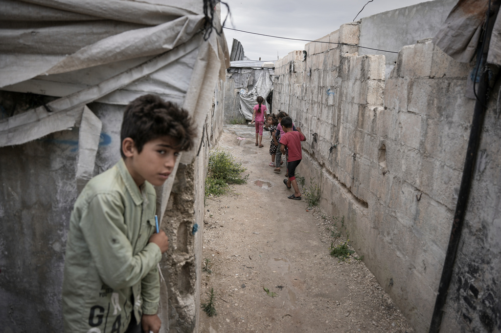 Children play through al-Karama camp, established in the early years of the Syrian conflict and built from scratch with light-brick structures covered with fabric to house internally displaced Syrians near the village of Atmeh, Idlib province, Syria, Tuesday, May 19, 2026. (AP Photo/Omar Albam)