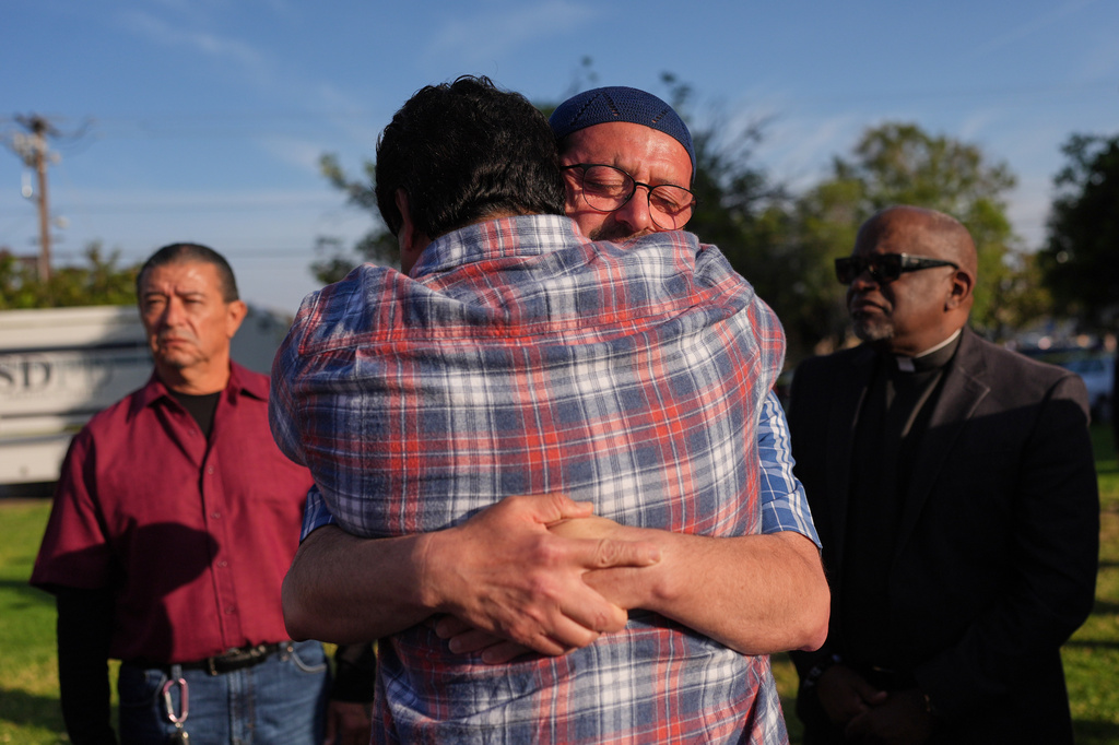 Imam Taha Hassane embraces another person as they attend a vigil, the day after a shooting, outside of the Islamic Center of San Diego, Tuesday, May 19, 2026, in San Diego. (AP Photo/Jae C. Hong)