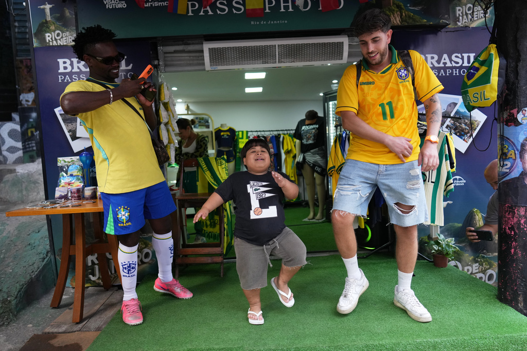 Influencer Narutinho, center, dances with Spain's tourist Ricard Sastre, right, at the Rocinha favela in Rio de Janeiro, on Sept. 2, 2026. (AP Photo/Silvia Izquierdo)