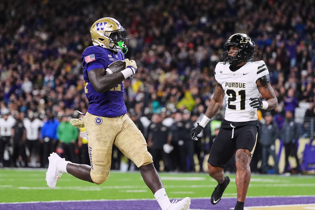 Washington running back Adam Mohammed scores against Purdue defensive back Tahj Ra-El (21) during the first half of an NCAA college football game, Saturday, Nov. 15, 2025, in Seattle. (AP Photo/Lindsey Wasson)