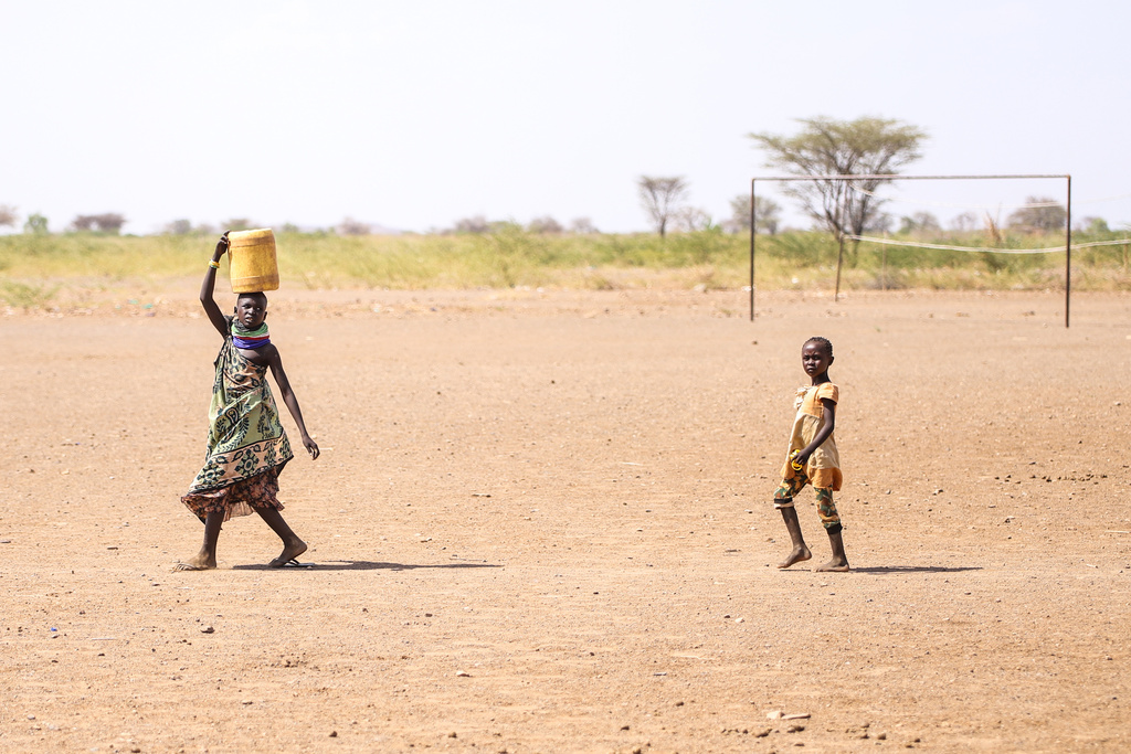 Children walk across an open field carrying water amid a prolonged drought in Nadunga Village, Turkana County, Kenya, Friday, Feb. 6, 2026. (AP Photo/Patrick Ngugi)