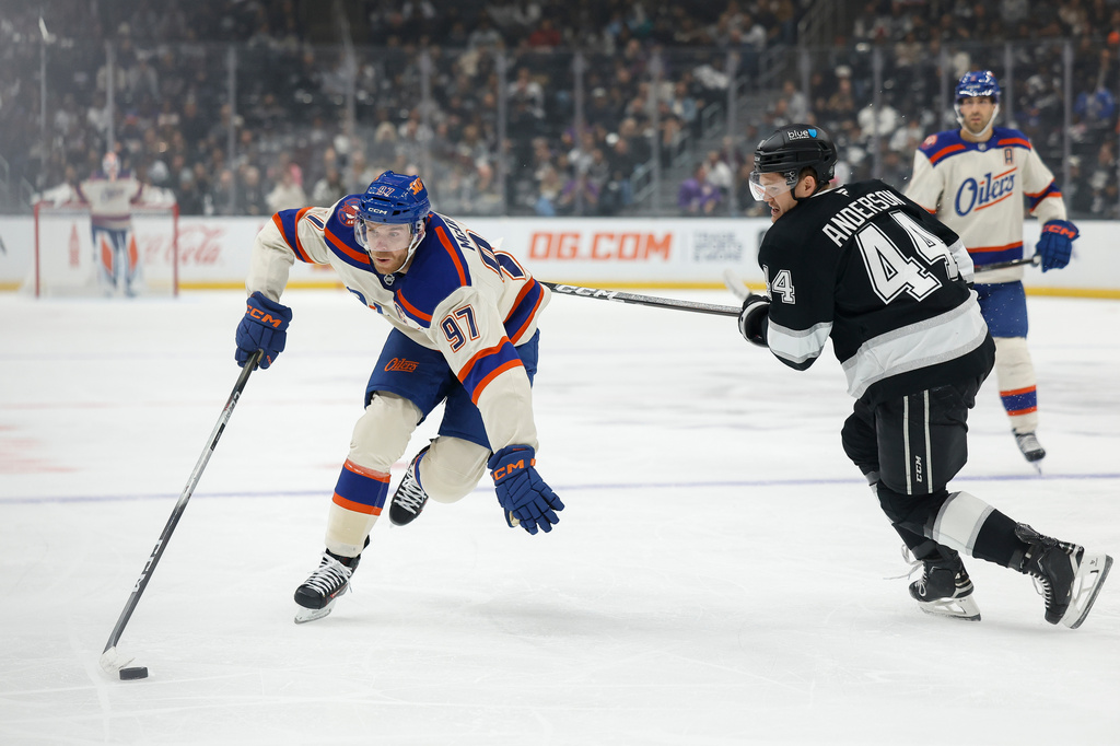 Edmonton Oilers center Connor McDavid (97), left, skates past Los Angeles Kings defenseman Mikey Anderson (44), right, with the puck during the first period of an NHL hockey game Tuesday, Oct. 13, 2026, in Los Angeles. (AP Photo/Caroline Brehman)