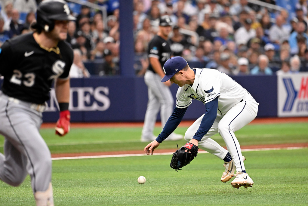 Chicago White Sox's Andrew Benintendi, left, runs to first base on a fielding error by Tampa Bay Rays pitcher Griffin Jax, right, during the first inning of a baseball game Sunday, Aug. 2, 2026, in St. Petersburg, Fla. (AP Photo/Jason Behnken)