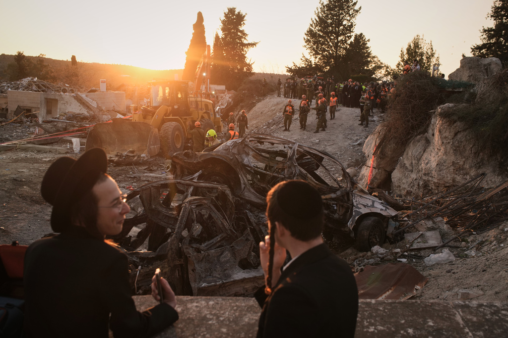 Ultra-Orthodox Jewish men look on as Israeli security forces operate at the site where several people were killed in an Iranian missile strike in Beit Shemesh, Israel, Sunday, March 1, 2026. (AP Photo/Leo Correa)